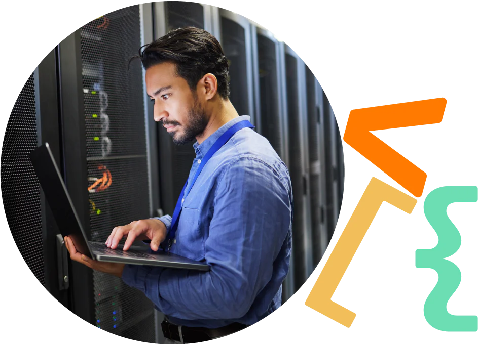 Man working on a laptop in a server room with server racks in the background